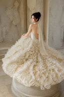 Champagne ruffle ball gown with voluminous skirt in seated editorial view