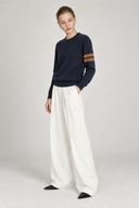 Aveline navy wool sweater styled with white wide-leg trousers, three-quarter view
