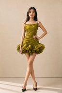 Posed front view of the olive green ruched mini dress with a layered petal ruffle hem