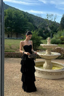 Black strapless maxi formal dress with layered ruffle skirt in a garden