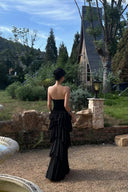 Back view of black strapless tiered ruffle maxi formal dress outdoors