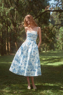 VOGSION blue and white floral garden party wedding guest midi dress photographed in motion outdoors