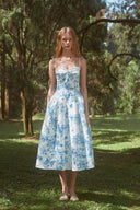 VOGSION Bluebell Garden blue and white floral midi wedding guest dress shown full length at an outdoor garden venue