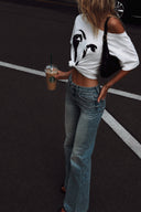 Close-up street style look featuring the VOGSION ÉCLIPSE Petite Off-Shoulder Graphic Tee, a petite-friendly oversized white graphic T-shirt paired with relaxed light wash denim and a minimalist black shoulder bag for an effortless summer casual outfit
