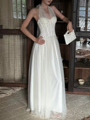 Close detail of Vogsion Elara Petite Ivory Corset Tulle Maxi Dress with structured bodice, soft halter neckline, and white quilted bag