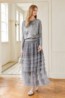 Model wearing the VOGSION Elowenne grey ombre tiered tulle maxi skirt in a bright interior