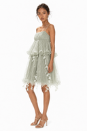 Model wearing Vogsion Emerald Fairy Garden Dress, a sage green tulle fairycore mini dress with romantic ruffle layers on a white studio background
