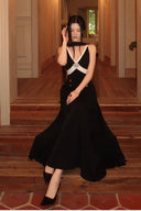 Seated front view of the Vogsion Éternelle black and white formal maxi dress, highlighting the built-in padded cups, crystal brooch and sweeping floor-length skirt.