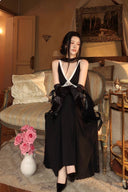 Model seated on a vintage sofa wearing the Vogsion Éternelle brooch evening dress with black gloves, white contrast trim, built-in bra and flowing maxi skirt.