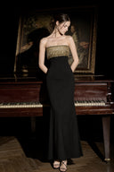 VOGSION black and gold beaded fringe strapless formal maxi dress posed by an antique piano