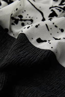 Close-up of the black textured fabric and sheer white splatter-print contrast panel