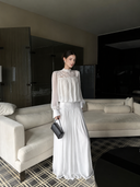 VOGSION Isolde romantic white cotton lace maxi dress in a standing hotel-suite view.