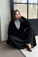 Nerine layered knit two-piece set styled with black trousers in a relaxed seated lifestyle look