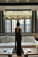 Back view of black open-back formal maxi dress with scarf tails