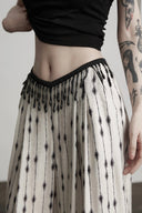 Angled close-up of the fixed black beaded fringe at the waistband