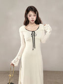 Close-up of the black ribbon neckline and floral lace cuffs on an ivory petite cotton-blend maxi dress