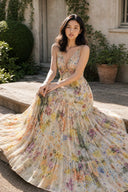 Seated model in the VOGSION Solenne flowy floral maxi dress outdoors