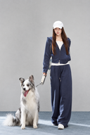 Model wearing the Sorelle petite navy zip-up hoodie and wide-leg pant set, standing beside a dog.