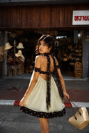 Back view of Vogsion Velvandis Off Shoulder Dot Mini Dress (Sage Green Polka Dot) showcasing the open back, off-shoulder design, airy babydoll silhouette and statement polka dot scarf. A lightweight mini dress for summer vacations, beach holidays, city escapes and effortless old money style.