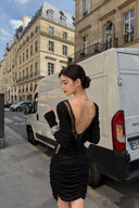 VOGSION Vespera black ruched mini dress with deep lace-trim open back, three-quarter street view