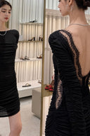 Front and back mirror view of VOGSION Vespera black open-back ruched mini dress