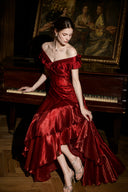 Crimson red satin formal maxi dress with cascading ruffles, seated view