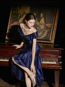 Deep navy satin ruched formal maxi dress with cascading ruffles, seated view