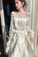 White long sleeve maxi dress styled with the included silver chain belt and crystal illusion neckline