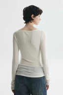 Back view of white sheer long sleeve layering top styled with denim