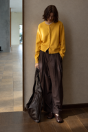 Brown wool-blend trousers styled with a yellow cardigan and large black bag.
