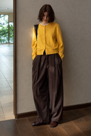 Brown wool-blend pleated barrel-leg trousers styled with a yellow cardigan, front view.