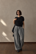 Grey high-waisted pleated barrel-leg trousers styled with a black short-sleeve knit.