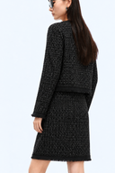 Back view of the black wool-blend tweed jacket and matching skirt with fringe edging.
