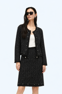 Front view of a black wool-blend tweed jacket and knee-length skirt set with beaded trim.