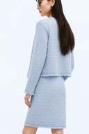 Back view of the light blue tweed jacket and matching skirt with fringed hems.